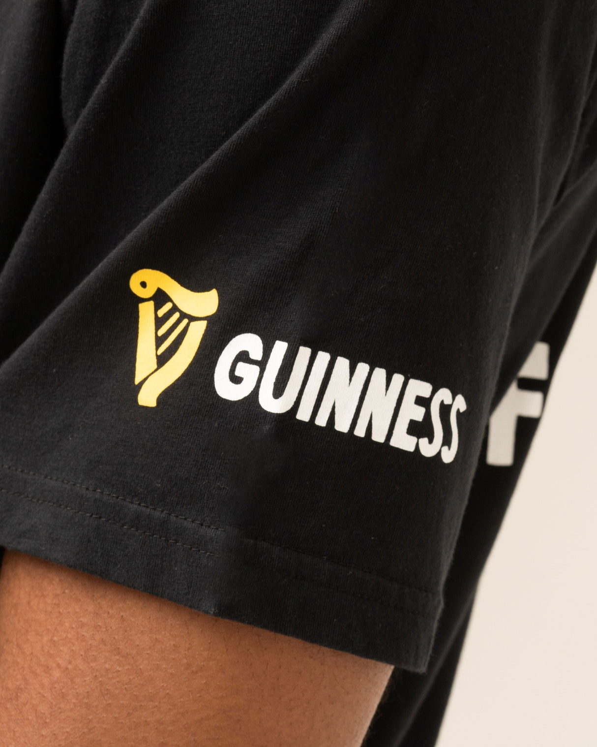 Black t-shirt with Guinness logo on a person's arm