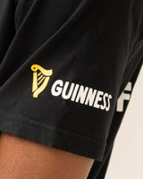 Black t-shirt with Guinness logo on a person's arm