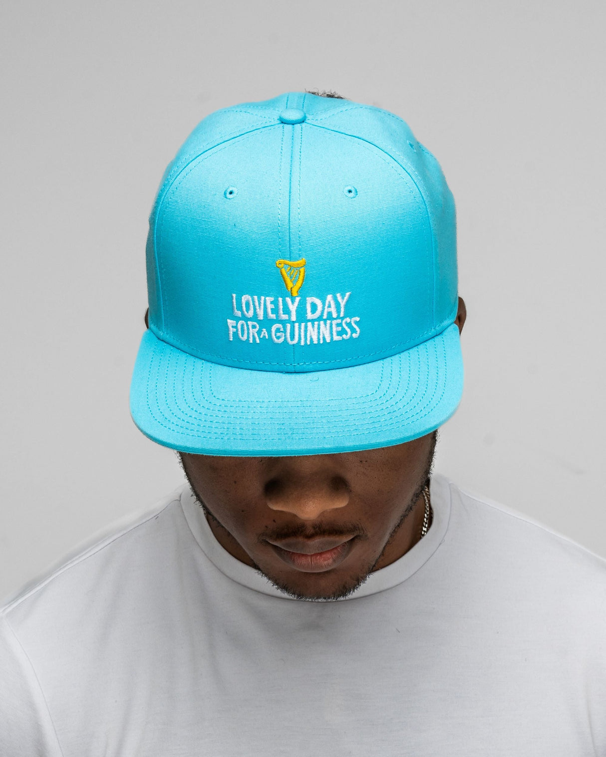 Person wearing a blue cap with 'Lovely Day for Guinness' text on a gray background