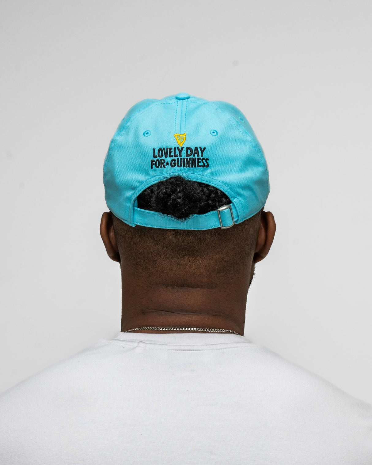 Person wearing a light blue cap with text on the back against a plain background