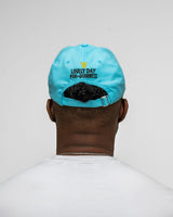 Person wearing a light blue cap with text on the back against a plain background