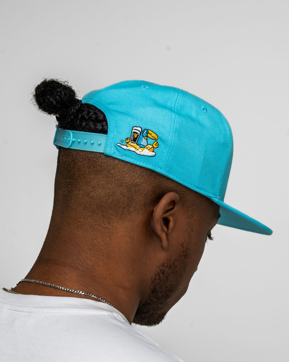 Person wearing a turquoise cap with a logo on a plain background