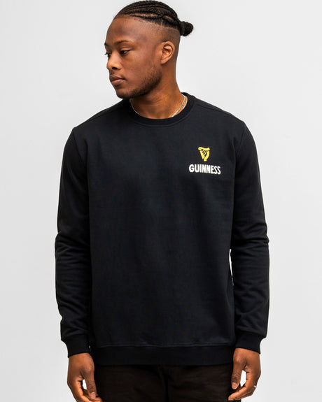 Person wearing a black Guinness sweatshirt on a light gray background