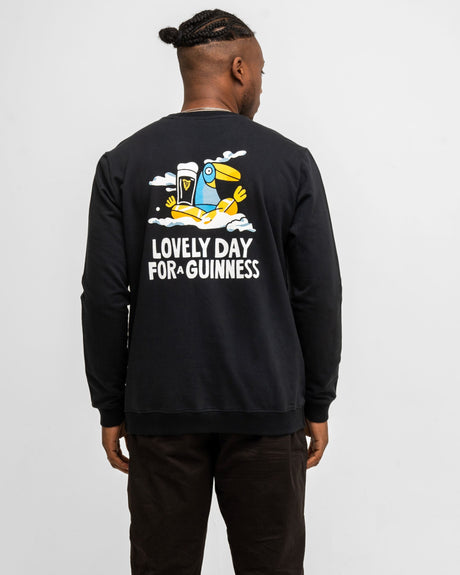 Person wearing a black sweatshirt with a graphic and text on the back, standing against a white background