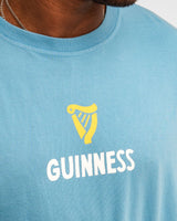 Person wearing a blue Guinness t-shirt with a yellow harp logo.