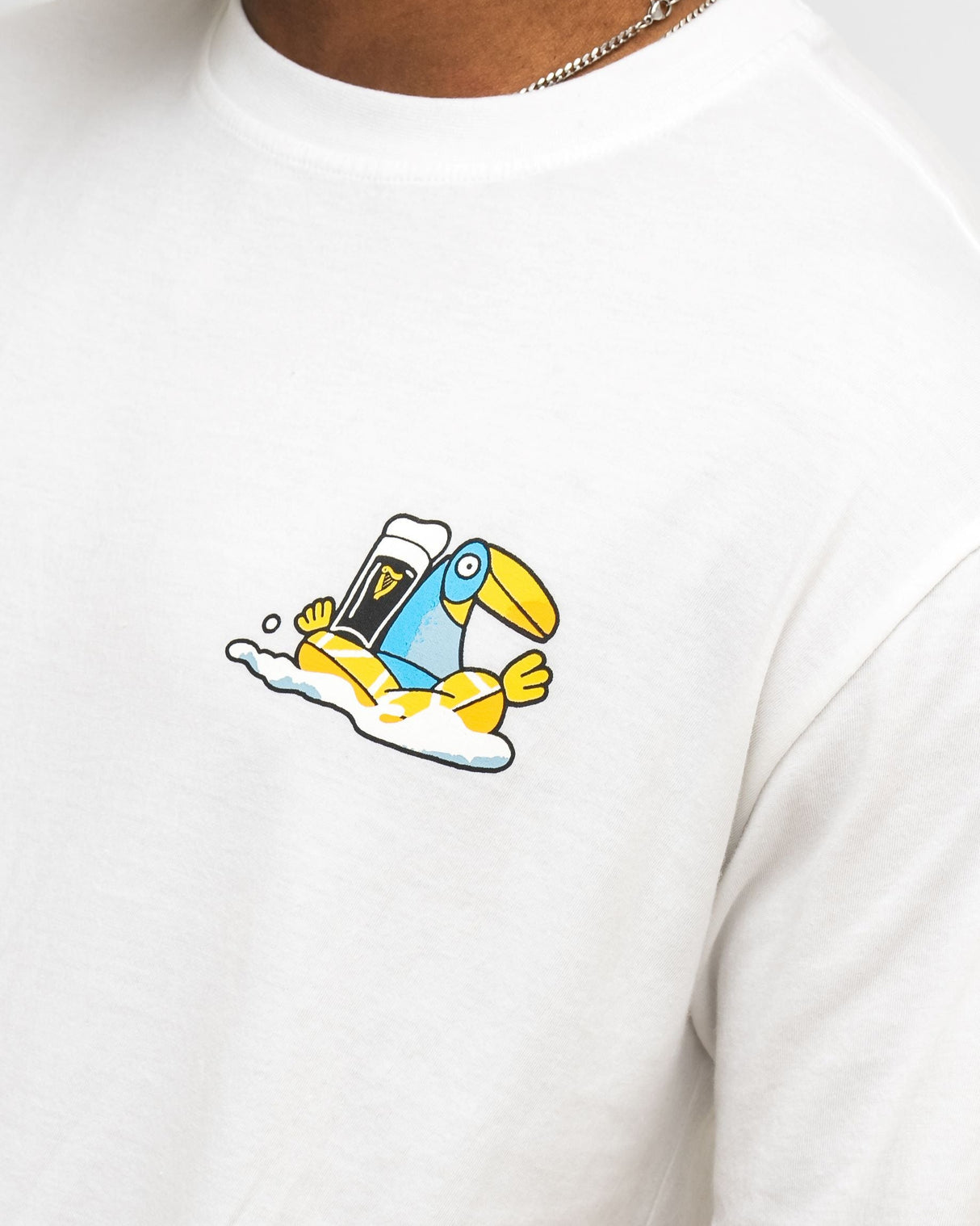 White t-shirt with a colorful graphic of a bird holding a glass bottle on a white background