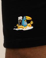 Black shorts with a colorful toucan holding a beer graphic on a beige background