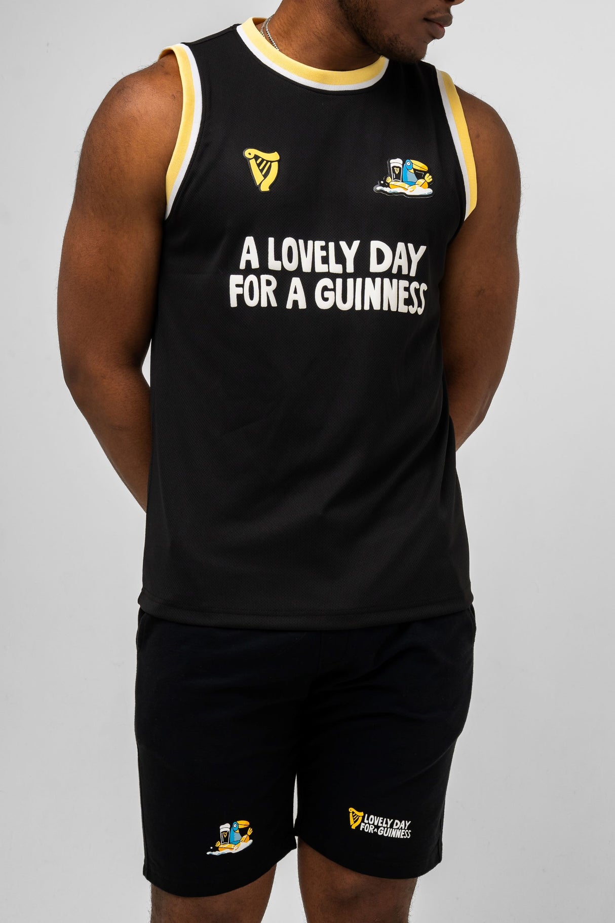 Person wearing a black sleeveless shirt and shorts with Guinness branding and text.