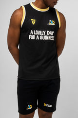 Person wearing a black sleeveless shirt and shorts with Guinness branding and text.