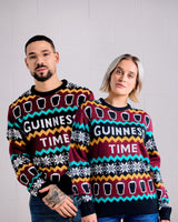 Two people wearing colorful Guinness-themed sweaters against a plain background