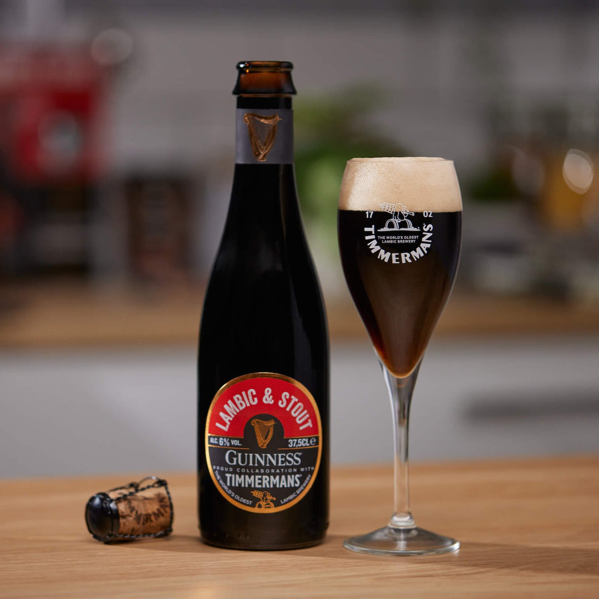 Image of a Guinness x Timmermans Lambic and Stout Bottle with a flute glass containing the Lambic and Stout.