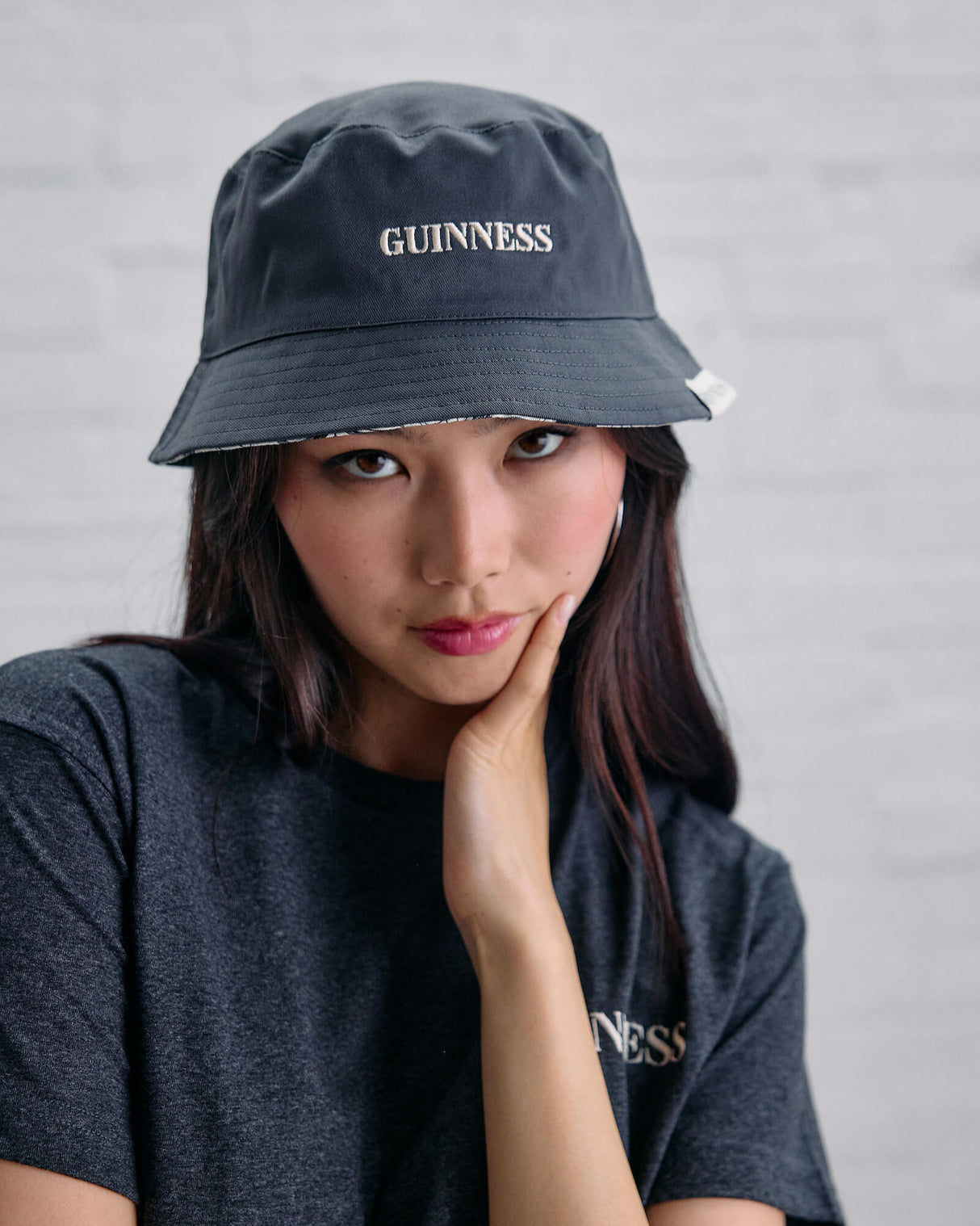 Person wearing a Guinness bucket hat and t-shirt against a gray background