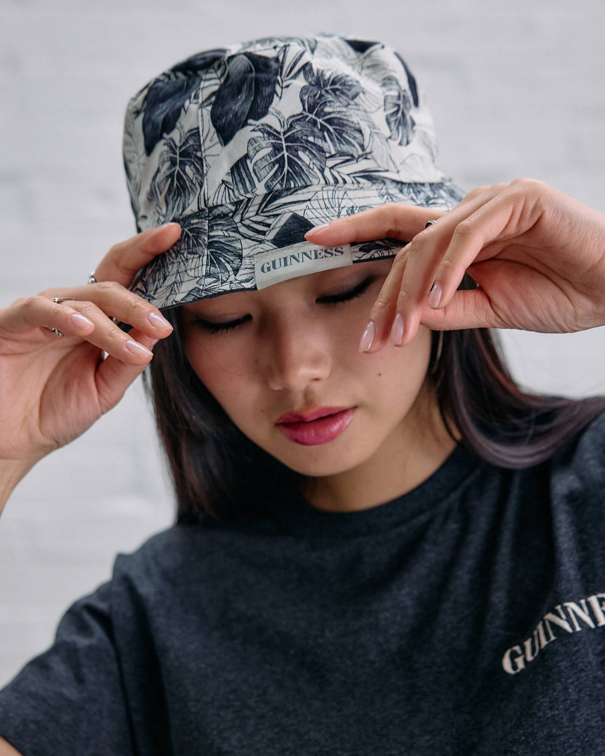 Person wearing a floral-patterned cap and a dark t-shirt with 'Guinness' branding.
