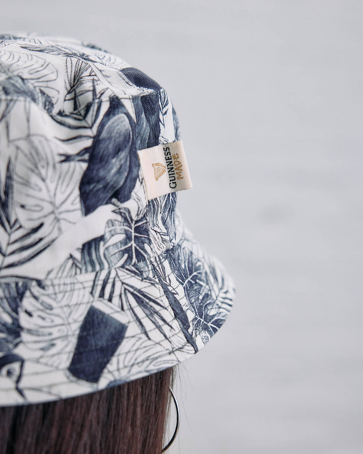 Bucket hat with leaf pattern and visible brand label on a plain background