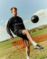 Person playing soccer on a field with a Guinness-branded shirt.