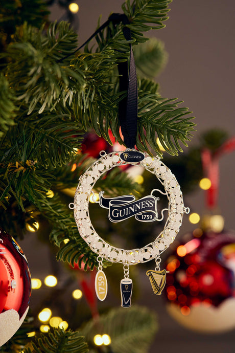 Guinness ornament hanging on a Christmas tree with blurred lights in the background