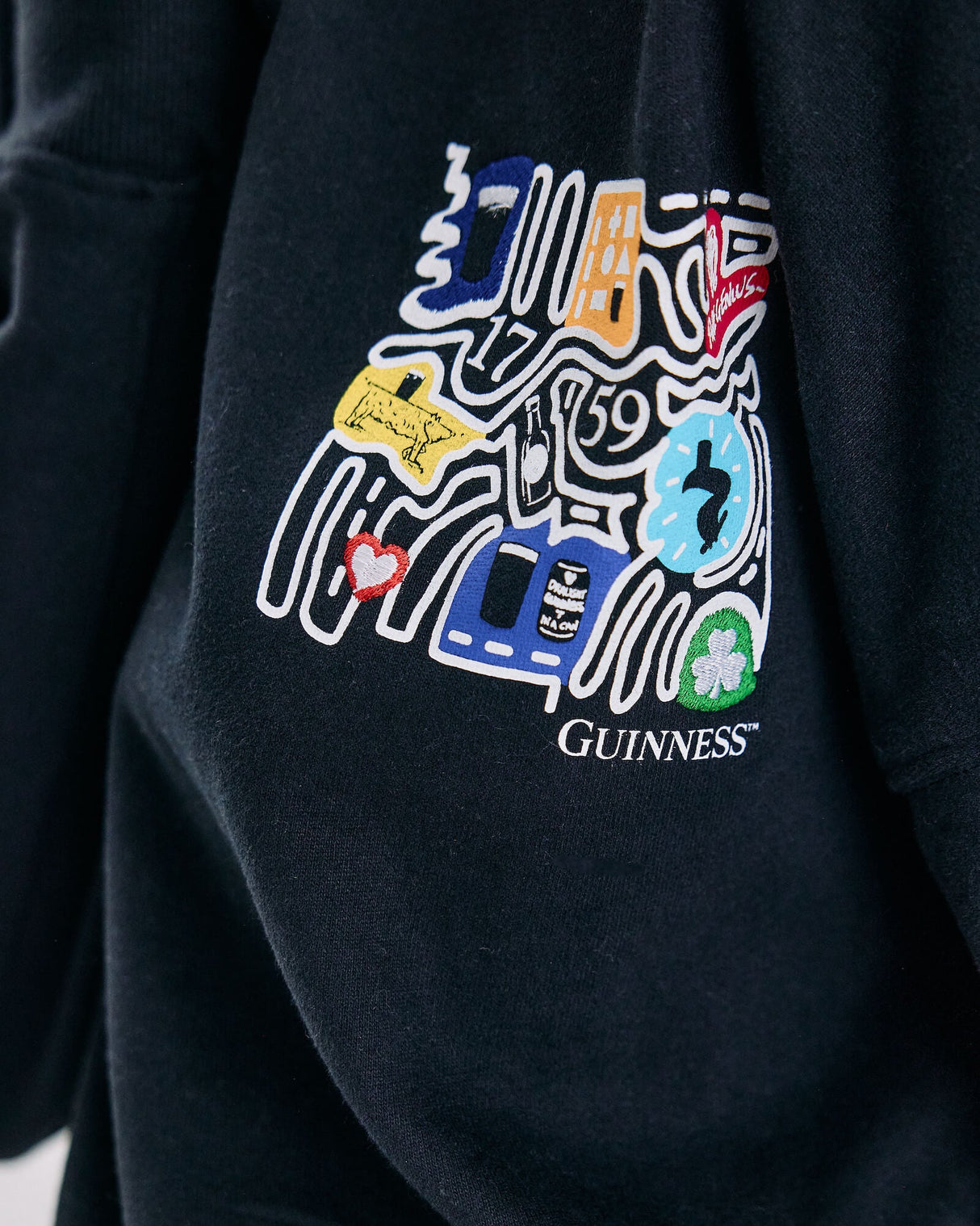 Detail shot of the Model wearing the Guinness Storehouse Exclusive Black Sweater with stylized Dublin map on the chest.