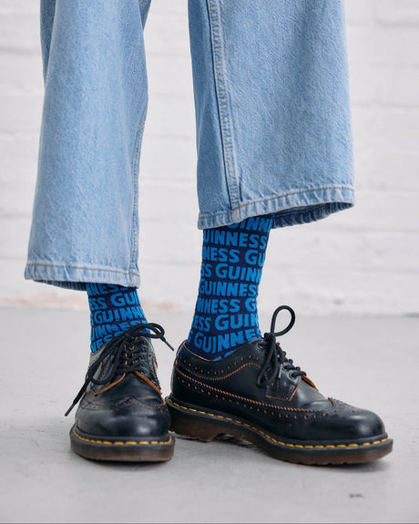 Model wearing the Guinness Storehouse Exclusive blue socks with Guinness logotype pattern.
