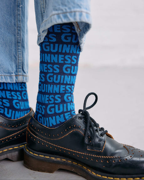 Model wearing the Guinness Storehouse Exclusive blue socks with Guinness logotype pattern.