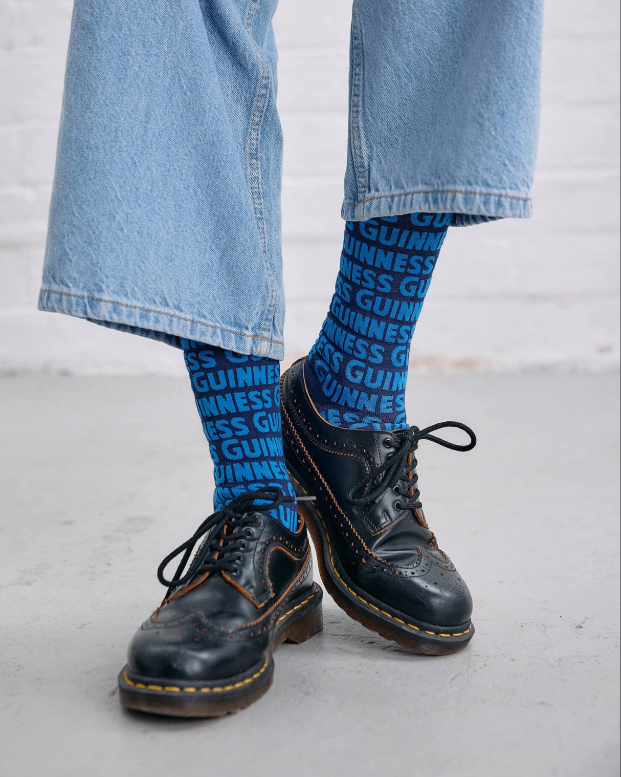 Model wearing the Guinness Storehouse Exclusive blue socks with Guinness logotype pattern.