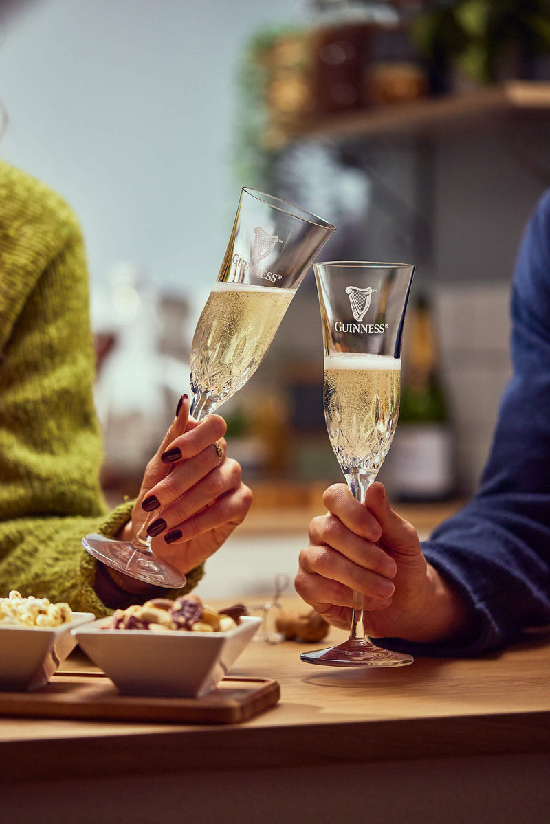 Two people drinking prosecco from the Guinness X Waterford crystal flute glass.